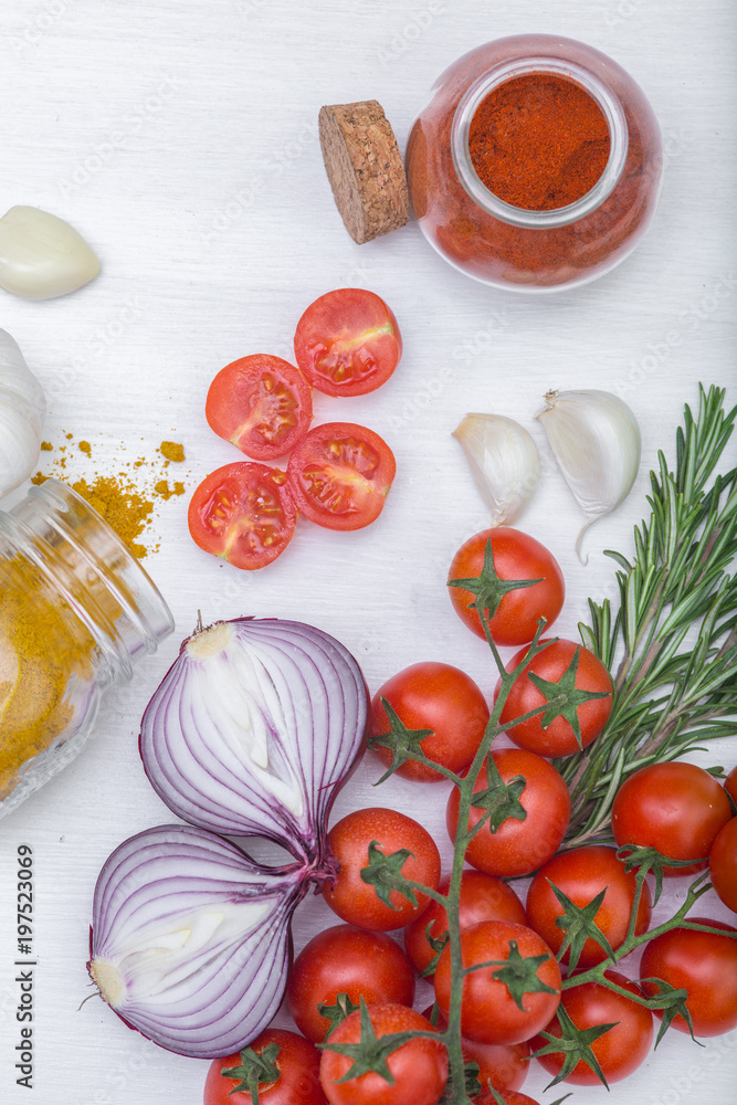 Bunch of tomatoes with garlic, rosemary, curry and chili pepper on white background Bunch of tomatoes with garlic, rosemary, curry and chili pepper on white background
