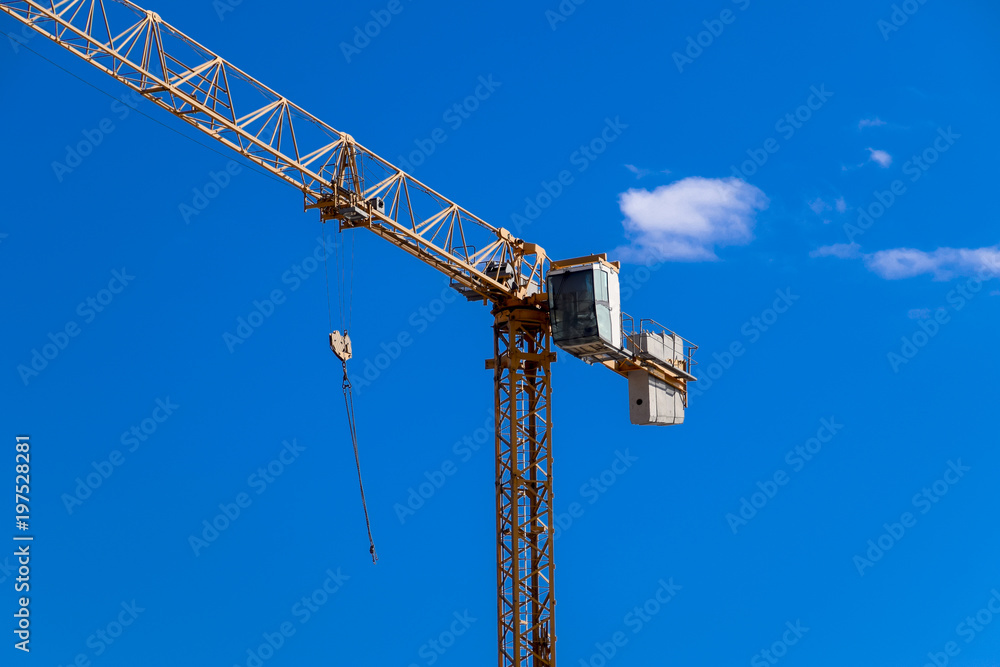 Tower building crane against the blue sky and sun. Construction of new buildings with a crane. Tower crane Tower building crane against the blue sky and sun. Construction of new buildings with a crane. Tower crane
