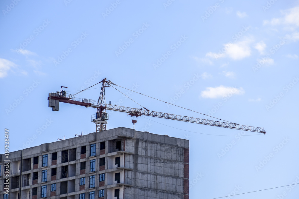 Tower building crane against the blue sky and sun. Construction of new buildings with a crane. Tower crane