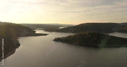 Flying over magical mystic lake sunrise near a misty forest pivot aerial push in shot photo