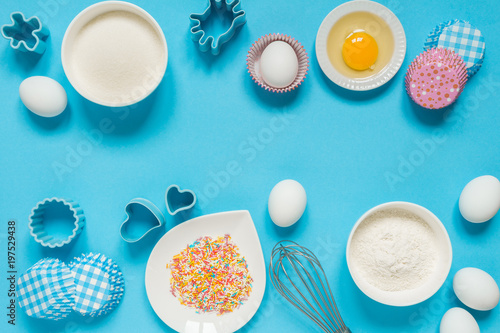 concept of the Easter bakery, various products for home baking, sugar, eggs and flour, coconut munt, top view, empty space for text on a blue background in the style of pop art mocap layout