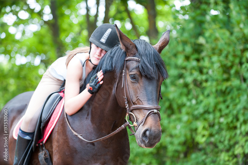 Young teenage lady-equestrian embracing her favorite frend-chestnut horse.