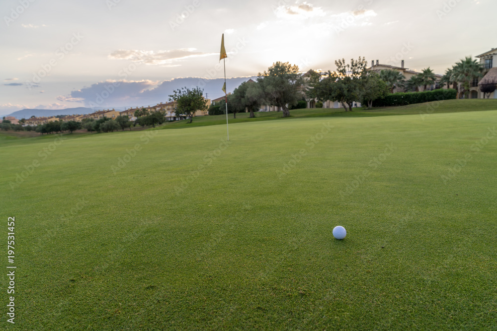 Obraz premium Golf ball on green fairway blue cloudy summer sky in the background