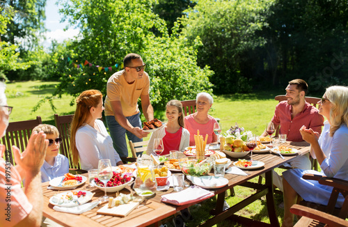 leisure  holidays and people concept - happy family having festive dinner or barbecue party at summer garden