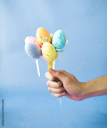 Man holding Easter eggs on a stick on a blue background photo