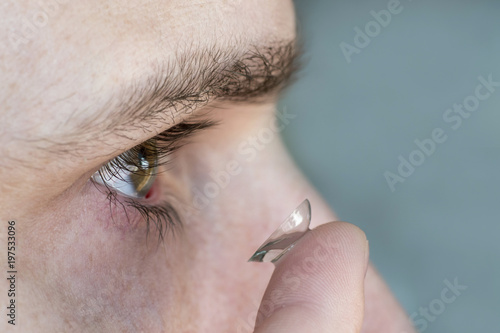 male eye close-up, contact lens on finger