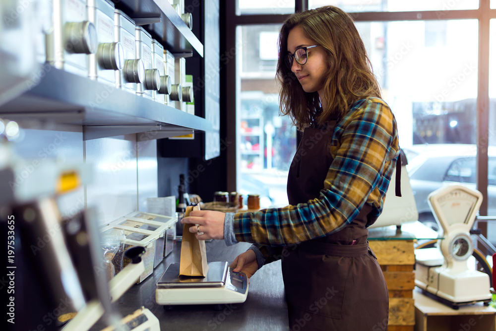 Beautiful young saleswoman weighing coffee beans in a retail store selling coffee. Beautiful young saleswoman weighing coffee beans in a retail store selling coffee.