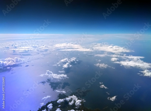 aerial view of the Mediterranean sea taken from an airplane with dark blue sky and clouds reflected on the water and an island in the bottom of the image