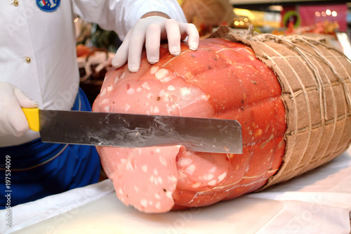 Chef slices the mortadella di Bologna with the knife