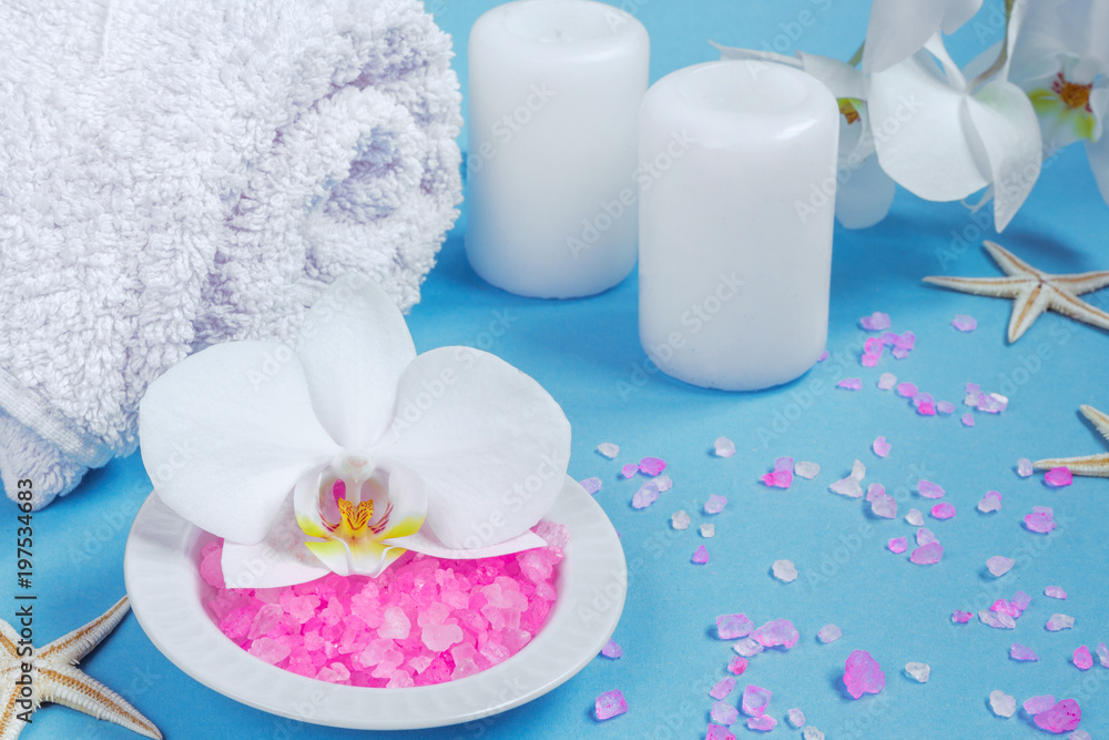 Spa background, flat layout with pink sea salt, candles and aroma oils and beauty care products on a blue background Spa background, flat layout with pink sea salt, candles and aroma oils and beauty care products on a blue background