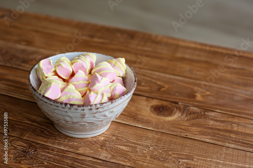  pink marshmallows in a white porcelain bowl on a wooden table