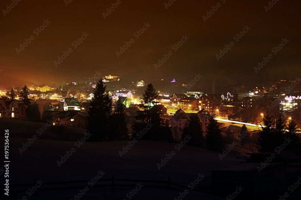 Ski village at night with slope lights, Carpathians