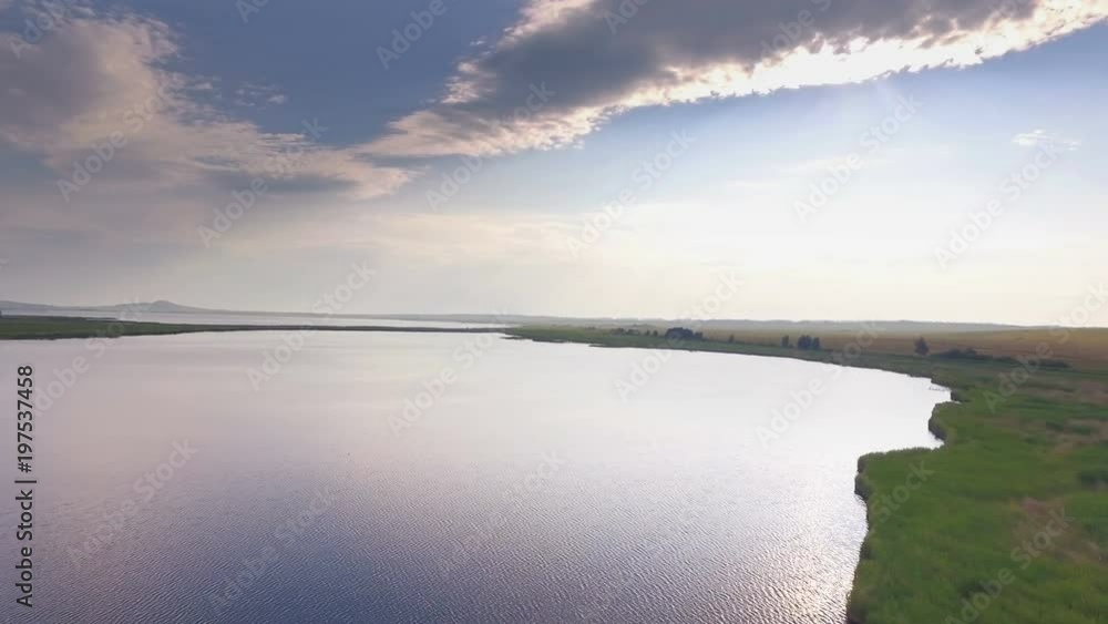 AERIAL: Colorful landscape of endless lakes with mountain and hills on a background. Reflections of sky on water surface. Seagulls and ducks fly over the lake. AERIAL: Colorful landscape of endless lakes with mountain and hills on a background. Reflections of sky on water surface. Seagulls and ducks fly over the lake.