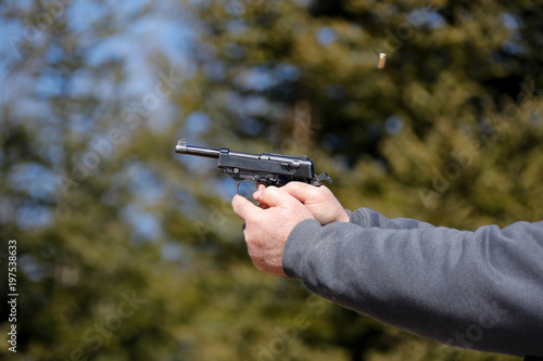Close-up of a handgun being fired; ejected shell in the air.