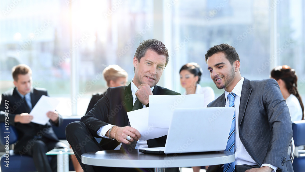 business partners discuss financial issues sitting in the lobby business partners discuss financial issues sitting in the lobby