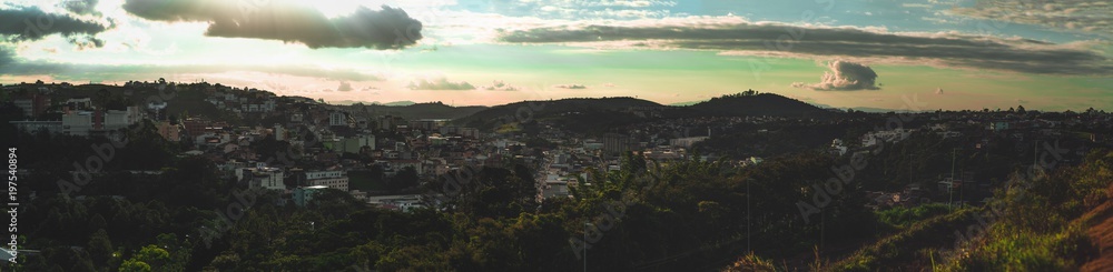 Wide panoramic shot from a high point of a small city Juiz de Fora in the Minas Gerais state of Brazil: hills with favelas, different districts of the town, parks, and trees, the streets with the cars