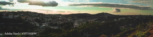 Wide panoramic shot from a high point of a small city Juiz de Fora in the Minas Gerais state of Brazil: hills with favelas, different districts of the town, parks, and trees, the streets with the cars