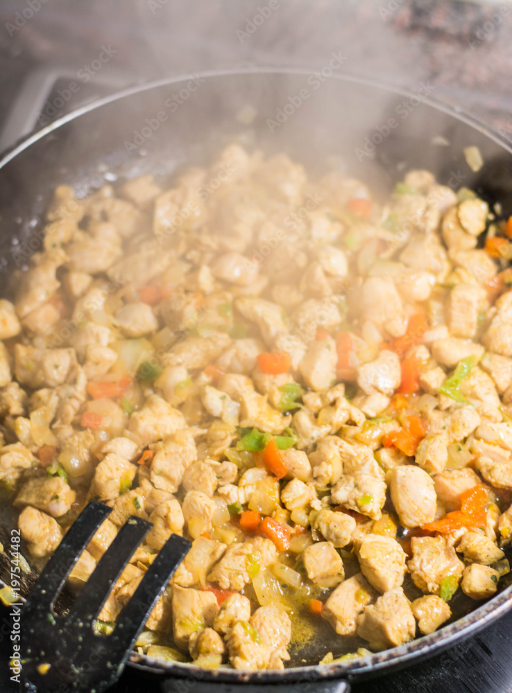 Cooking burrito in a pan with chicken, pepper, tomato for fajitas typical Latin America food Cooking burrito in a pan with chicken, pepper, tomato for fajitas typical Latin America food