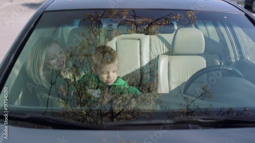 Little boy sitting in the car with his young mother 4k