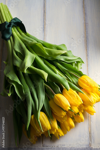 Bouquet of spring tulips flowers on white wooden background. Yellow tulips