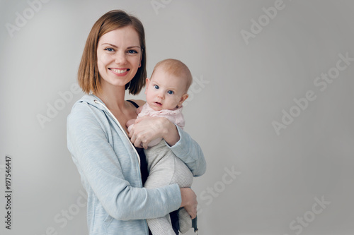 happy mom hugs a three-month-old baby. baby and mom are looking at the frame