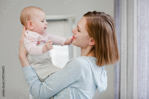 happy mom hugs a three-month-old baby