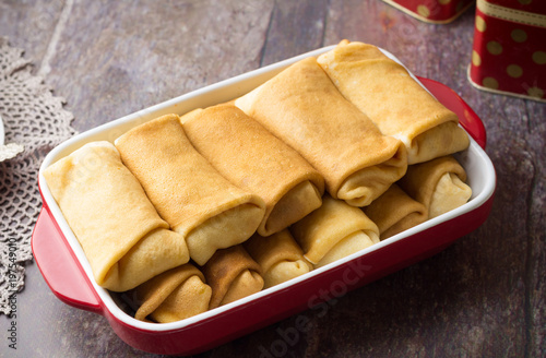 Pancakes stuffed with cottage cheese with sour cream and cup of tea. Breakfast. Sweet dessert of pancakes rolls.