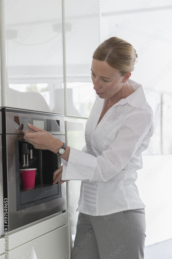 Mature woman preparing coffee in modern kitchen Mature woman preparing coffee in modern kitchen