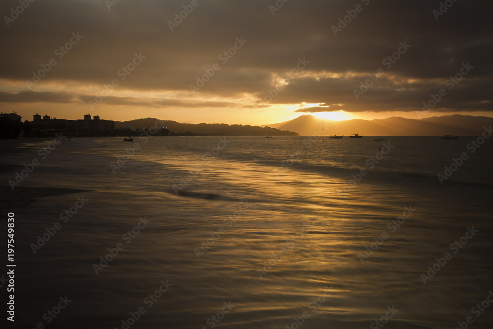 Sunset in 'Jurerê Internacional' beach. Golden light and colorful sky. Reflexes in the water. Florianópolis, Santa Catarina / Brazil