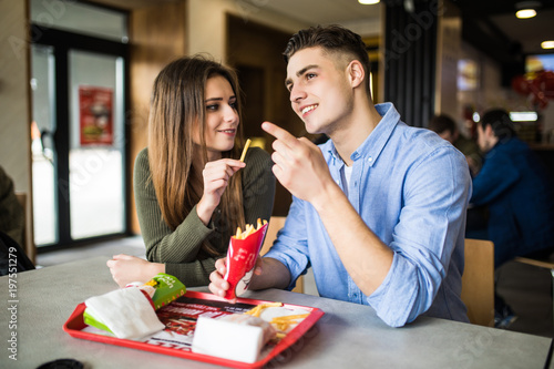 Dating in fast food. Handsome smiling couple enjoying in fries  having fun together. Consumerism  food  lifestyle concept