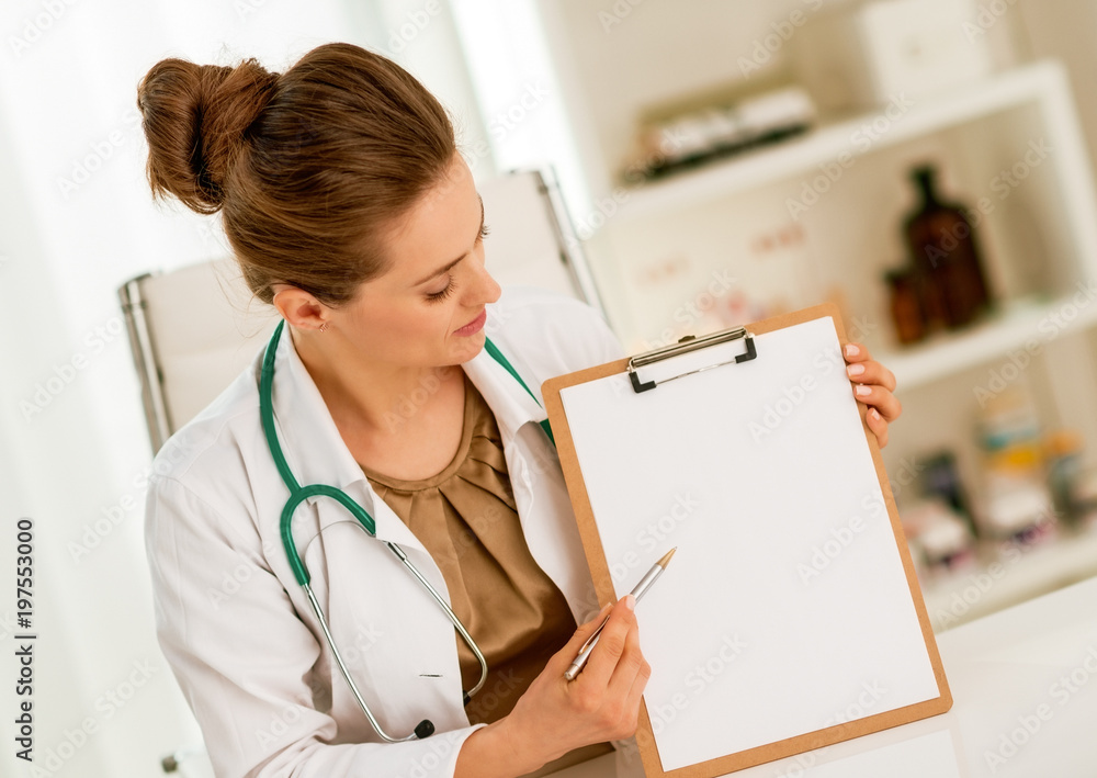 Happy medical doctor woman pointing in clipboard Happy medical doctor woman pointing in clipboard