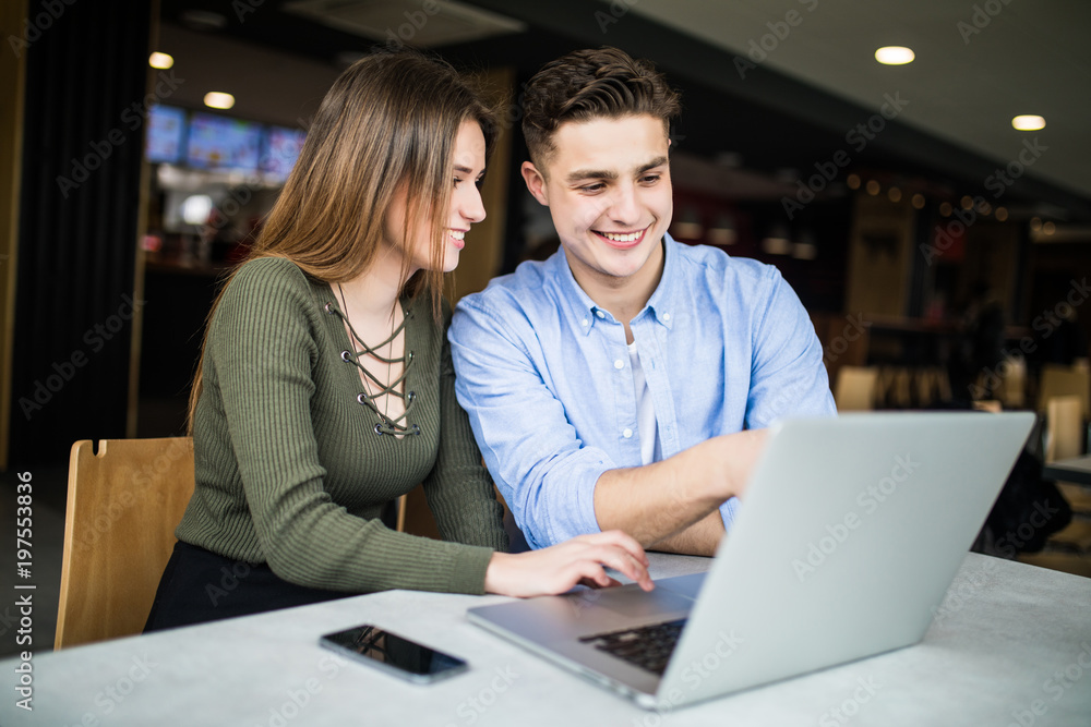 Fototapeta premium Young couple is working in cafe on laptop