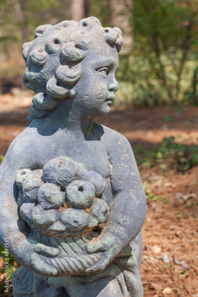 Stone statue of a child holding a basket of fruit Stone statue of a child holding a basket of fruit