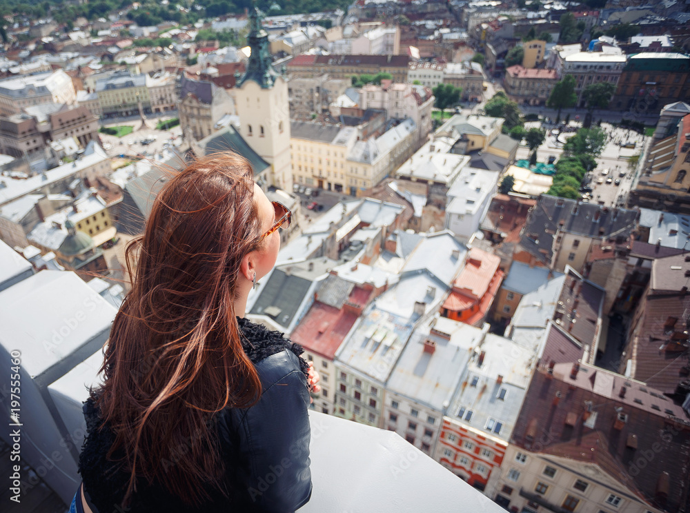 Back view of young woman enjoying Lviv city. Young girl tourist looking at a panoramic view of the city Lviv. Ukraine
