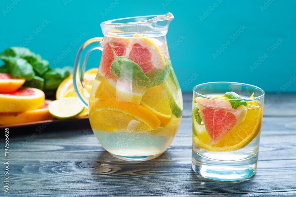 Refreshing healthy homemade citrus lemonade served in glass pitcher with fruit slices and basil on blue background, cold delicious summer drink Refreshing healthy homemade citrus lemonade served in glass pitcher with fruit slices and basil on blue background, cold delicious summer drink