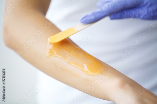 Master does epilation of hands with help of sugar paste hot wax in salon beauty.