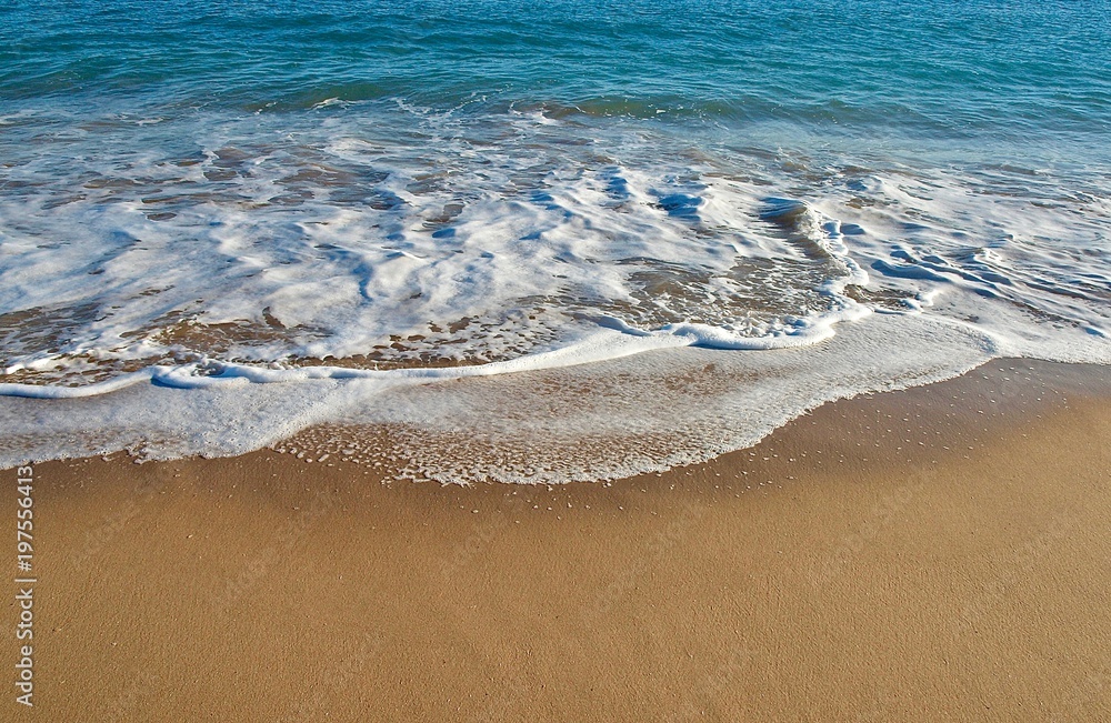 Wellen und türkis blaues Meer am feinen Sandstrand