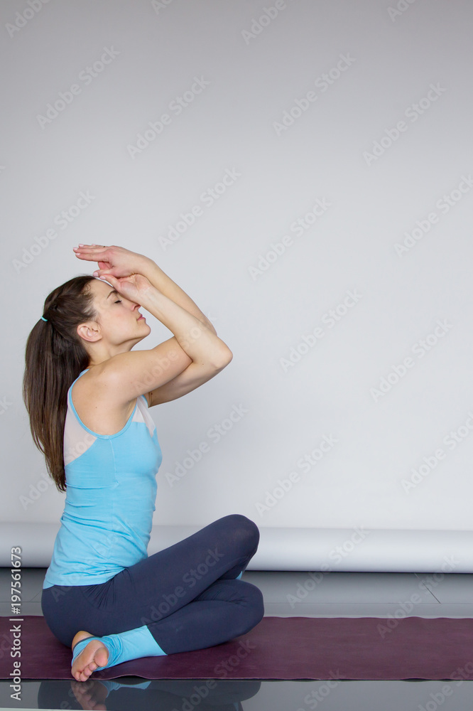 Obraz premium Young woman sitting in Cow Face pose Gomukhasana Copy space