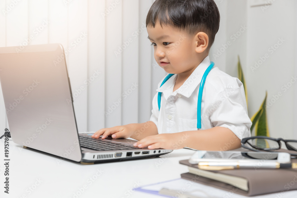 Young asian boy playing doctor and using computer laptop. Young asian boy playing doctor and using computer laptop.