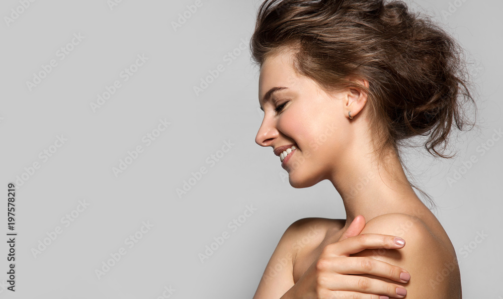 Obraz premium Piękna kobieta z doskonałą skórą i nagimi ramionami w profilu na szarym tle