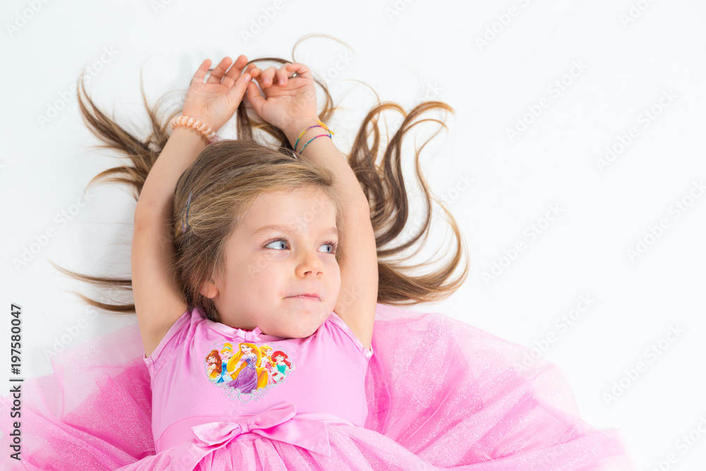 Bambina sorridente con abito rosa su sfondo bianco