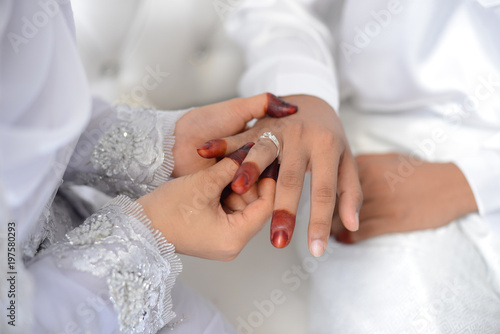 malay wedding groom bolstering gold ring on bride's finger