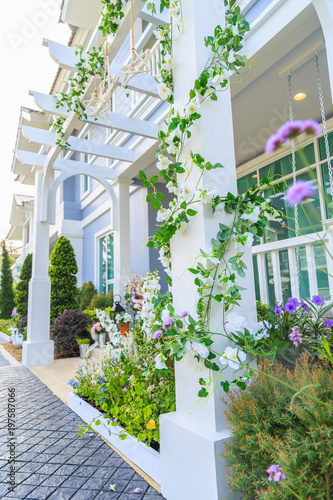 An artificial ivy with white flowers around the pillar with front yard background.