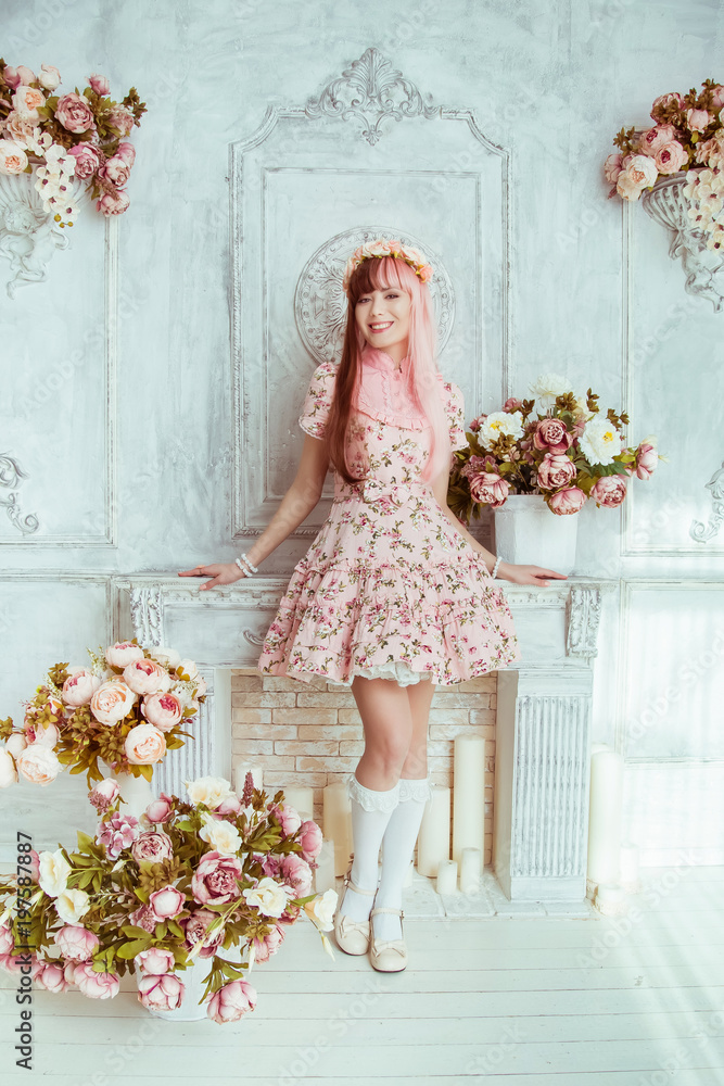 Beautiful young woman doll in a pink dress in a bright room and