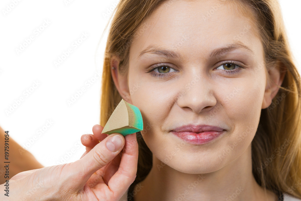 Woman applying foundation with sponge Woman applying foundation with sponge