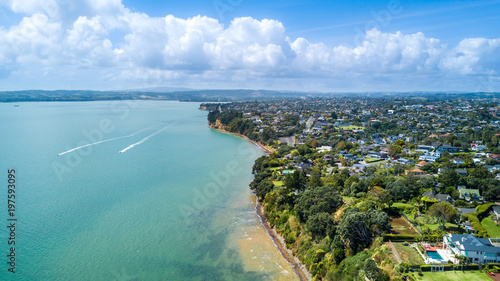 Aerial view on residential suburb on the top of rocky cliff, facing sunny harbour. Auckland, New Zealand.
