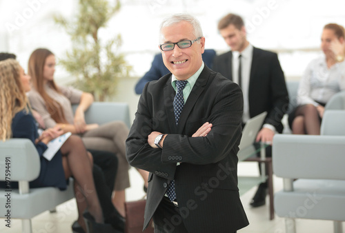 smiling senior businessman on the background of business team