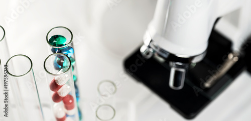 Laboratory Microscope, pills and test tubes. Scientific and healthcare research background.