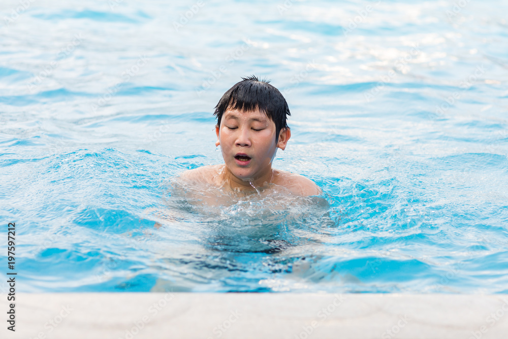 Happy Asian boy enjoing in the pool, summer holiday.