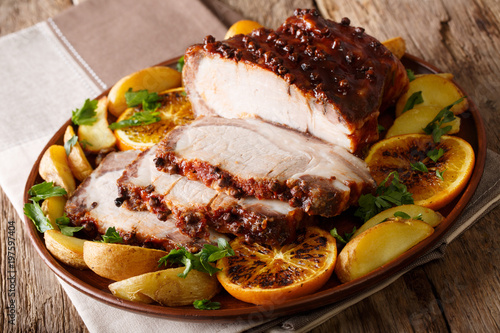 Christmas baked ham chopped slices with potatoes, oranges and apples close-up. Horizontal